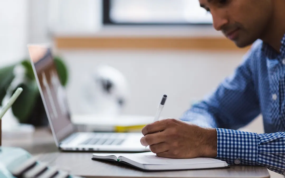 Application Checklist man at desk with laptop writing in notebook