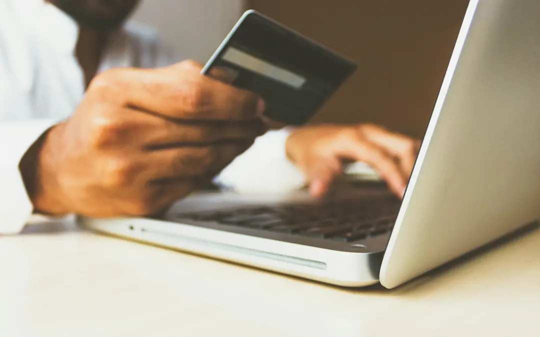 Credit Score man holding credit card while typing in laptop