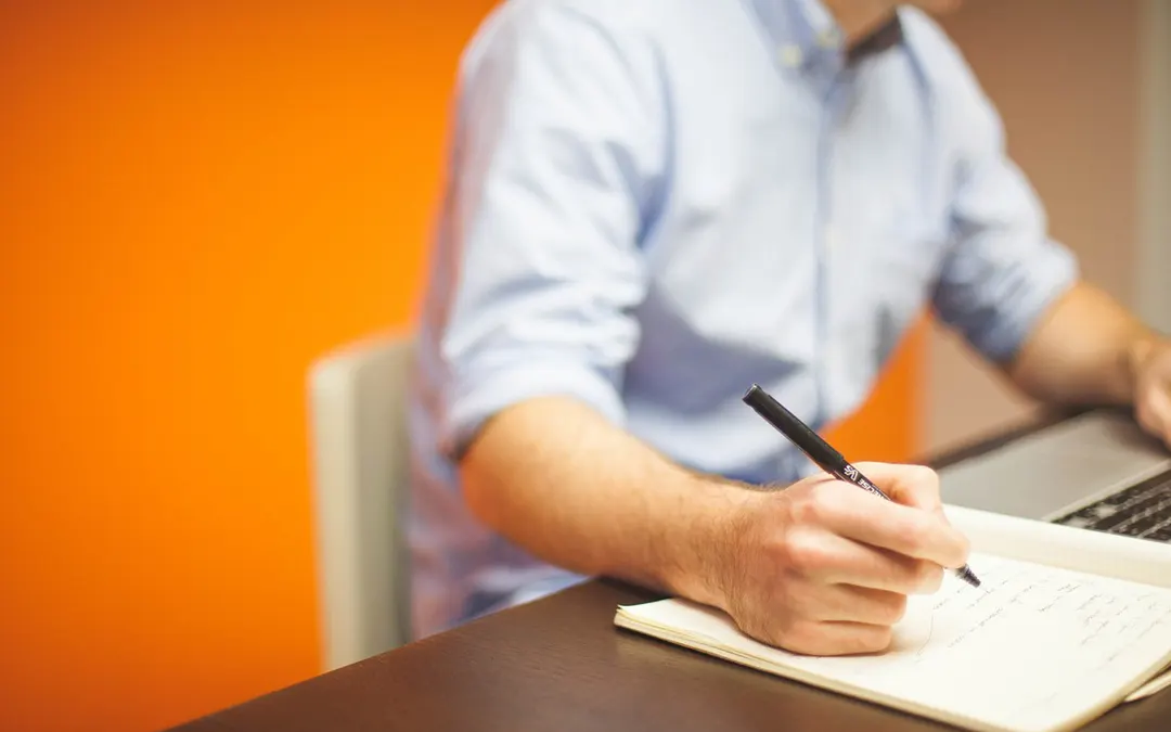 Refinance Your Home man writing in notebook at desk